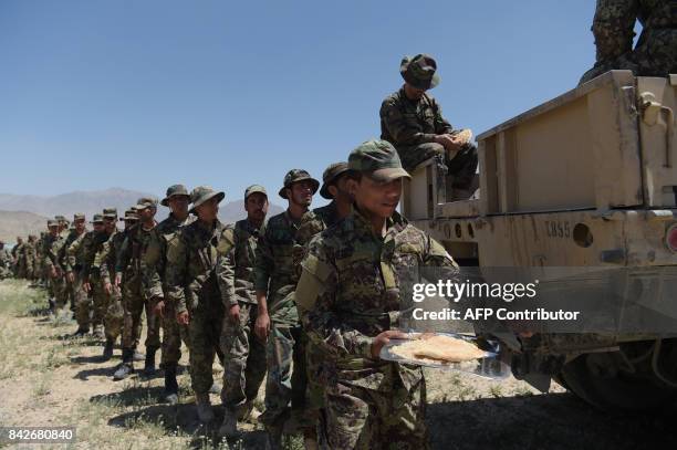 In this photograph taken on May 1 Afghan National Army soldiers line-up to get their lunch at the Kabul Military training centre in the outskirts of...