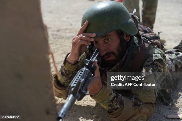 In this photograph taken on August 10 an Afghan commando adjusts his helmet during live firing exercises at Camp Morehead on the outskirts of Kabul....