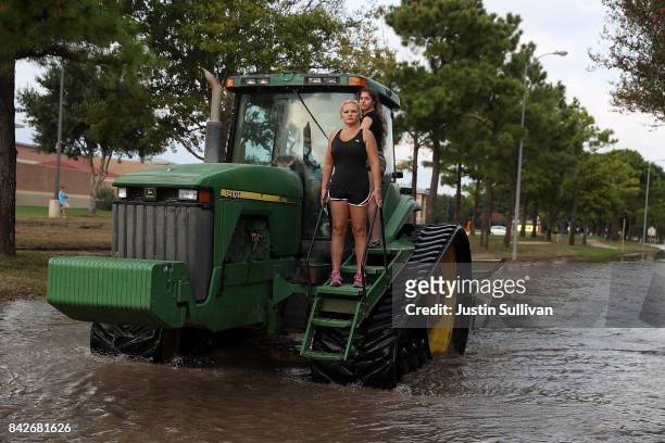 Two girls ride through floodwaters an a tractor on September 4, 2017 in Katy, Texas. Over a week after Hurricane Harvey hit Southern Texas, residents...