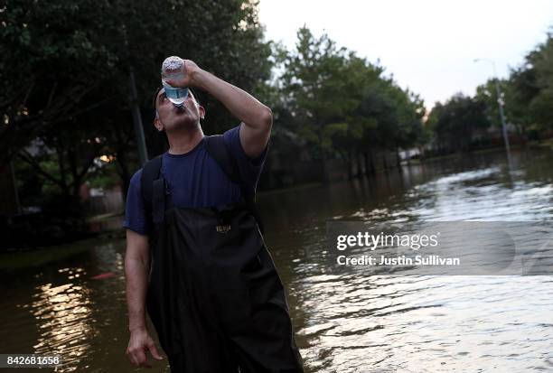 Samir Novruzov stops to drink water as he walks through a flooded street on September 4, 2017 in Katy, Texas. Over a week after Hurricane Harvey hit...