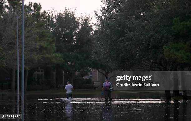 Two men walk through a flooded street on September 4, 2017 in Katy, Texas. Over a week after Hurricane Harvey hit Southern Texas, residents are...