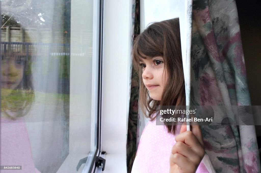 Young girl looks out of a window