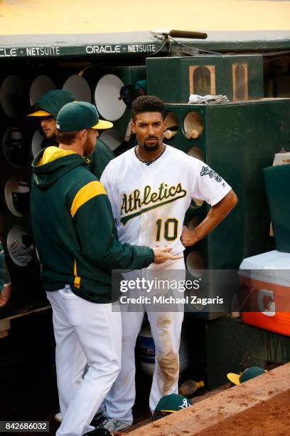 Jaycob Brugman and Marcus Semien of the Oakland Athletics talk in the dugout during the game against the Kansas City Royals at the Oakland Alameda...