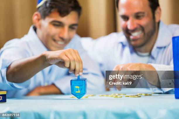 father and teenage son playing dreidel - geld stock pictures, royalty-free photos & images