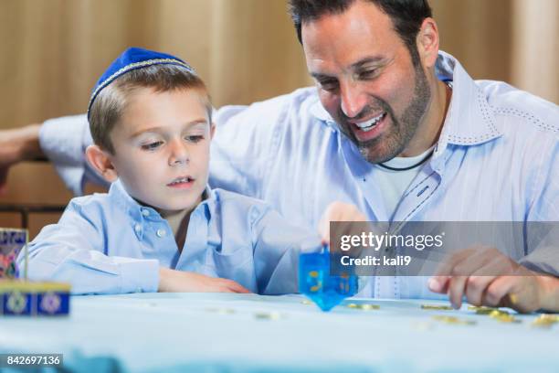 little boy and father playing dreidel - dreidel stock pictures, royalty-free photos & images