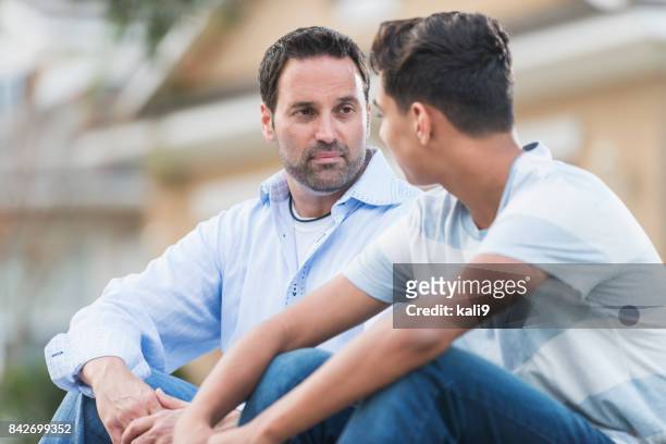 father sitting with serious teenage boy - serious teenager boy imagens e fotografias de stock