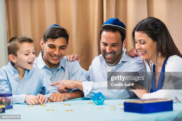 family of four playing dreidel game - skull cap stock pictures, royalty-free photos & images