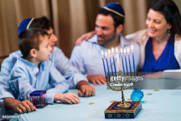 family of four celebrating hanukkah - jewish celebration stock pictures, royalty-free photos & images