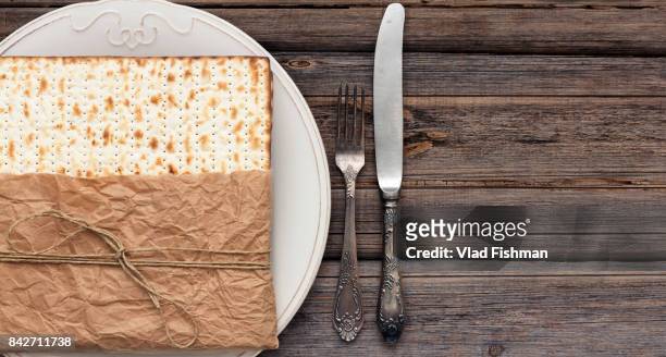stack of matzah or matza with a white plate and silverware on a vintage wood background presented as a gift with copy space - passover seder plate stock pictures, royalty-free photos & images