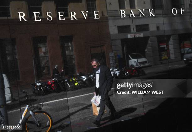 Two walk past the Reserve Bank of Australia sign in Sydney on September 5, 2017. - Australia's central bank set on the sidelines for the...