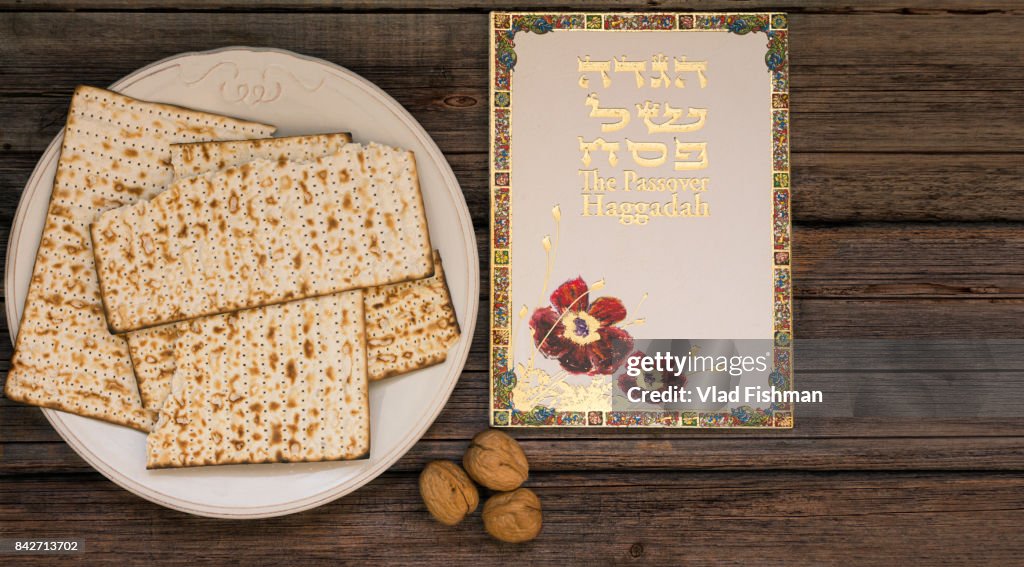 White plate  with matzah or matza and Passover Haggadah on a vintage wood background presented as a Passover seder feast or meal with copy space