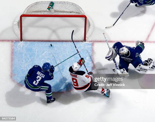 Zach Parise of the New Jersey Devils skates around Kevin Bieksa of the Vancouver Canucks and collects a goal on Jason LaBarbera during their game at...