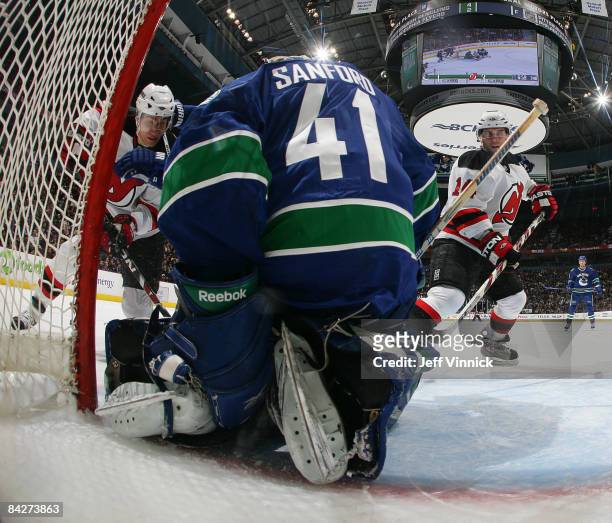 Brian Gionta of the New Jersey Devils and teammate Dainius Zubrus watch on as Curtis Sanford of the Vancouver Canucks makes a save during their game...