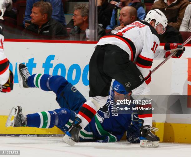 John Madden of the New Jersey Devils knocks Henrik Sedin of the Vancouver Canucks to the ice during their game at General Motors Place on January 13,...