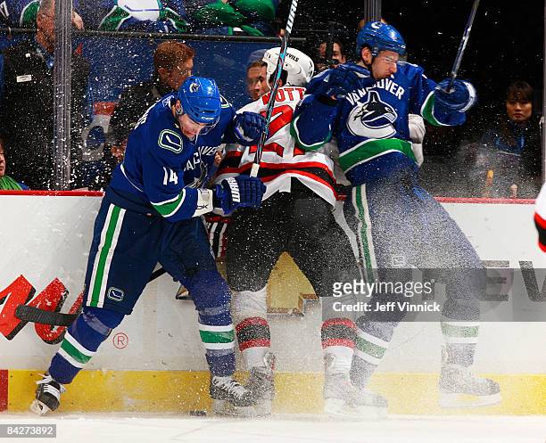 Mike Mottau of the New Jersey Devils gets sandwiched between Alex Burrows of the Vancouver Canucks and Ryan Kesler during their game at General...