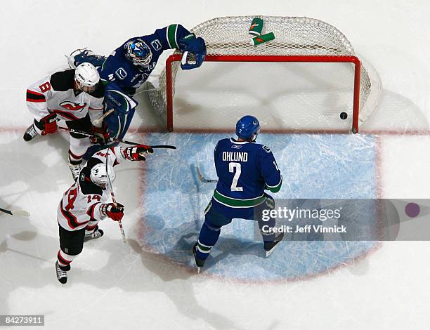 Mattias Ohlund of the Vancouver Canucks stands in the crease while goaltender Curtis Sanford crumples at the side of the net while Brian Gionta of...