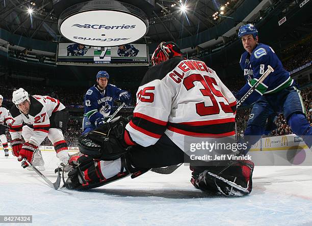 Mike Mottau of the New Jersey Devils and Kyle Wellwood and Willie Mitchell of the Vancouver Canucks look on as Scott Clemmensen of the New Jersey...