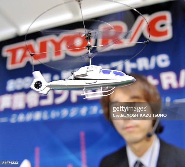 Japan's radio control toy maker Taiyo employee, wearing a headset, displays the new voice controled helicopter toy "New Hornet" which is enables to...