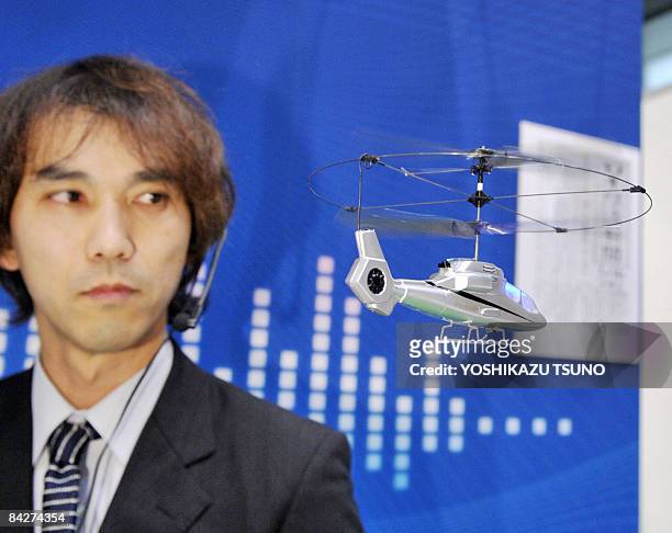 Japan's radio control toy maker Taiyo employee, wearing a headset, displays the new voice controled helicopter toy "New Hornet" which is enables to...