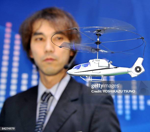 Japan's radio control toy maker Taiyo employee, wearing a headset, displays the new voice controled helicopter toy "New Hornet" which is enables to...