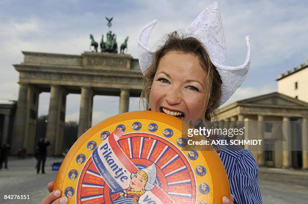 Woman dressed as a Dutch "Meisje Antje" poses with a cheese in front of Berlin's landmark the Brandenburg Gate on January 14, 2009 to promote the...