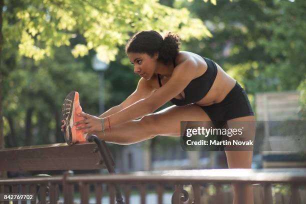 an athletic woman runner warming up - leg stretch girl stock-fotos und bilder
