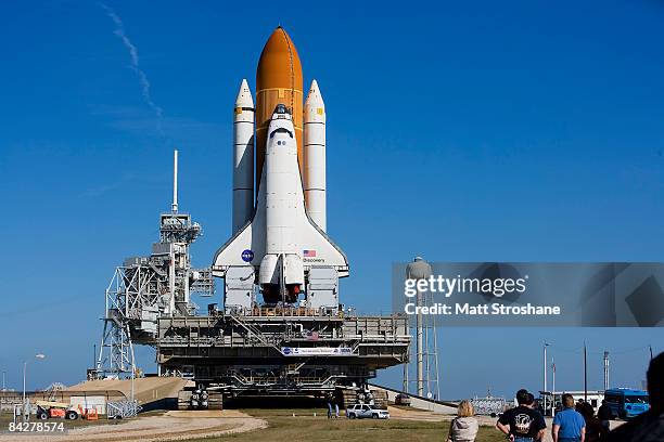 Workers watch as Space Shuttle Discovery moves atop the crawler transporter onto launch complex 39A at Kennedy Space Center January 14, 2009 in Cape...