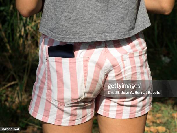 young girl in a striped shorts with a mobile phone in her pocket. spain - bottom stock pictures, royalty-free photos & images