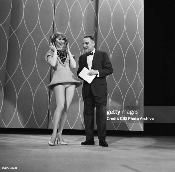 American commedienne Carol Burnett, a glass bowl over her head, and television show host Garry Moore perform together on an episode of 'The Garry...