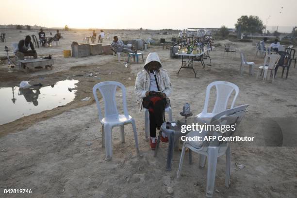 Detained African illegal immigrants smoke waterpipe during their free time in an improvised cafe outside the Holot detention center, located in...