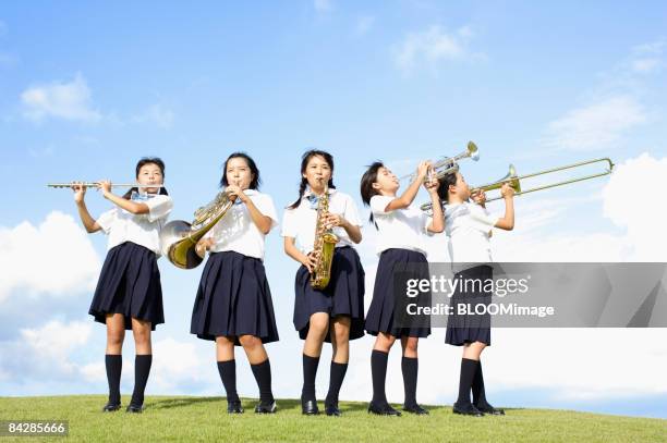 female students playing musical instruments - blaasinstrument stockfoto's en -beelden