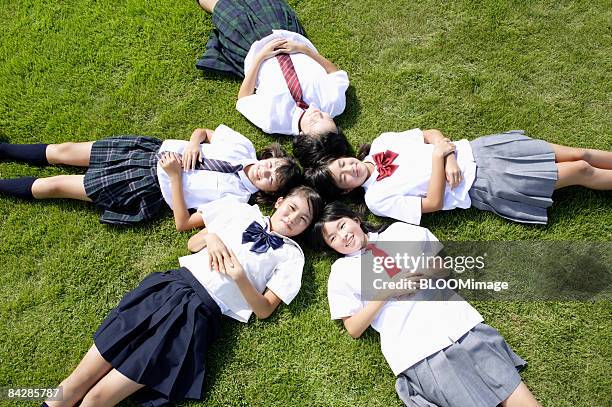 female students lying on grass with heads together - only japanese stock pictures, royalty-free photos & images