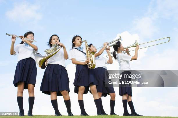 female students playing musical instruments - blaasinstrument stockfoto's en -beelden