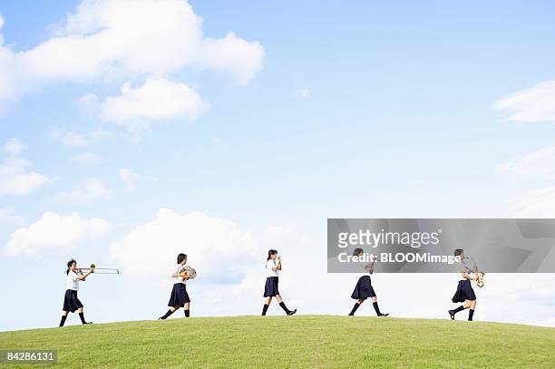 female students playing musical instruments, walking in line - studentessa di scuola secondaria foto e immagini stock