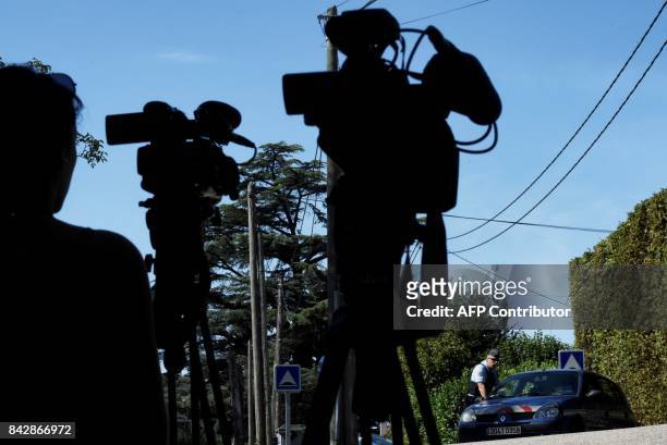 Journalists film French gendarmes standing next to their vehicles in front of the house of a man charged with kidnapping following the disapperance...
