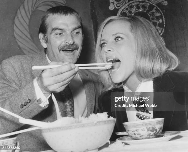 Welsh actor Stanley Baker demonstrates the use of chopsticks to actress Honor Blackman, during a photocall for their new film 'Grigsby' at Young's...