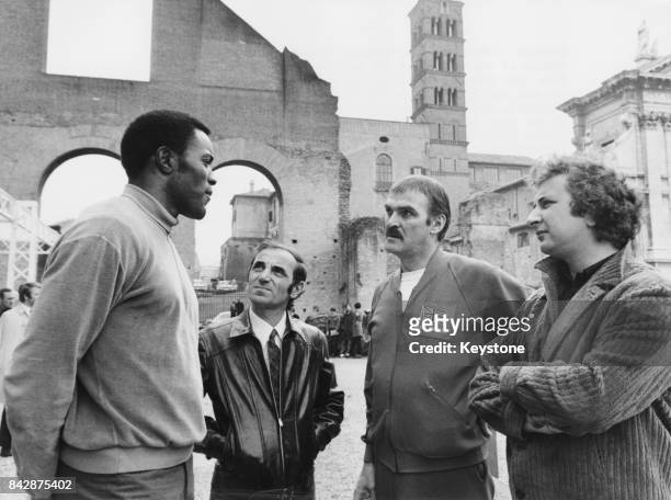 From left to right, Olympic champion Rafer Johnson, singer Charles Aznavour and actor Stanley Baker , with director Michael Winner near the Colosseum...