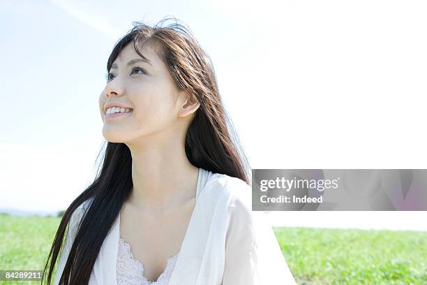 young woman looking up and smiling on grass - japanese woman looking up stock-fotos und bilder