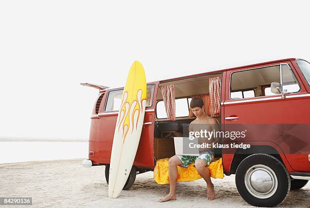 young surfer using laptop in van on beach - tampa beach stock pictures, royalty-free photos & images