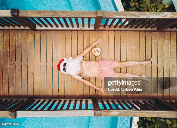 santa claus entspannen am pool - conceptualrealismtrend stock-fotos und bilder