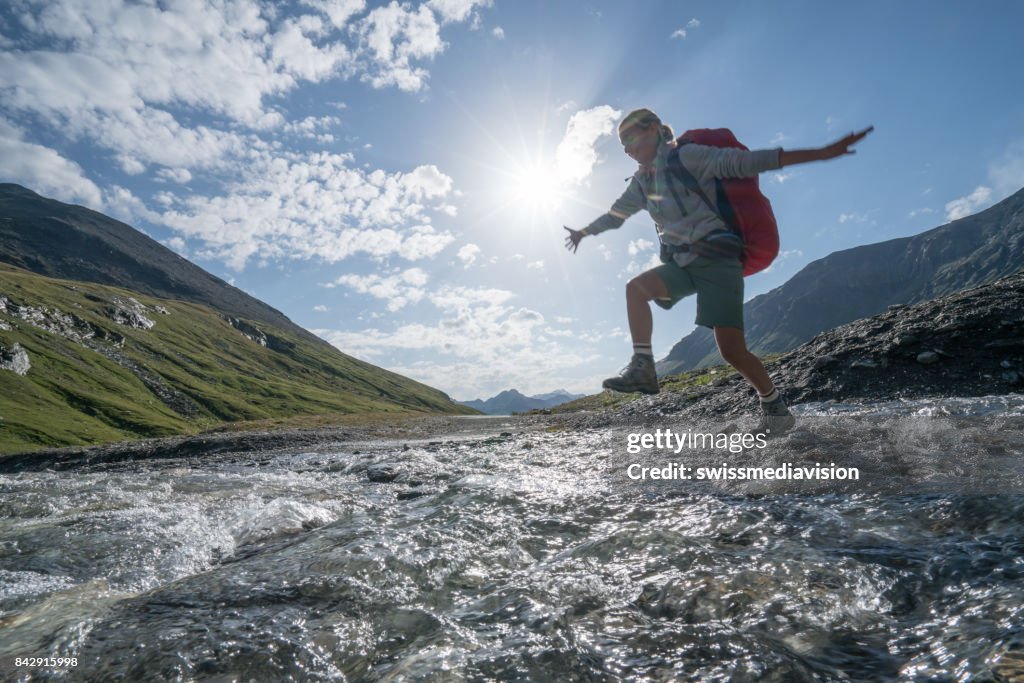 Joven salta de roca en el río de la montaña