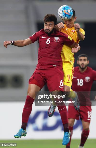 China's Xiao Zhi and Qatar's Ahmed Yasser Abdelrahman jump to head the ball during the FIFA World Cup 2018 qualification football match between Qatar...