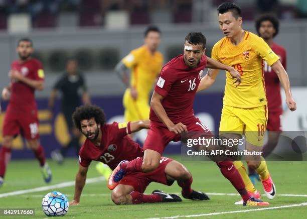 Qatar's Boualem Khaoukhi and his teammate Ahmed Mohamed Elsayed vie for the ball against China's Gao Lin during the FIFA World Cup 2018 qualification...