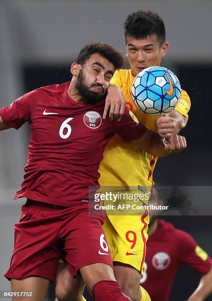 China's Xiao Zhi and Qatar's Ahmed Yasser Abdelrahman jump to head the ball during the FIFA World Cup 2018 qualification football match between Qatar...