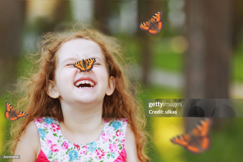 Förvånad curly flicka med en fjäril på näsan.