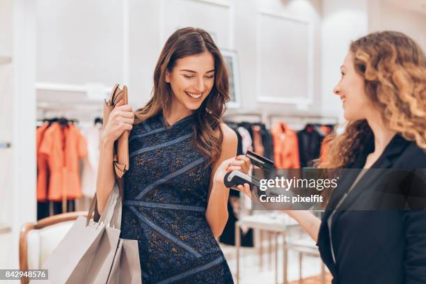 pago sin contacto de tarjeta de crédito en una tienda de lujo - compra por tarjeta de crédito fotografías e imágenes de stock