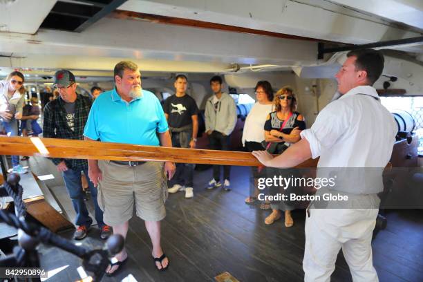 Constitution crew member Ryan Boyle demonstrates how the capstan is used to raise and lower the anchor from below deck on the ship in the Charlestown...