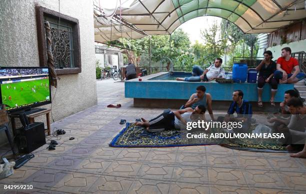 Syrian football fans watch the FIFA World Cup 2018 qualification football match between Iran and Syria on television at a house in the...