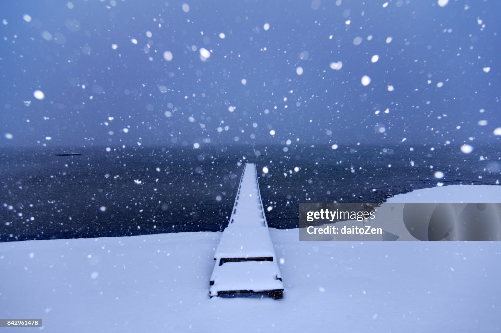 Winter wonderland landscape at Lake Chiemsee with snow-covered jetty and falling snow, Gstadt, Upper Bavaria, Germany