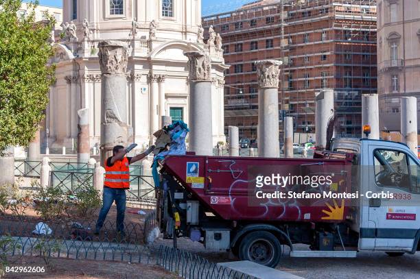 Waste disposal worker throws away clothing belonging to refugees evicted by police from Piazza Venezia, who had returned following their removal from...